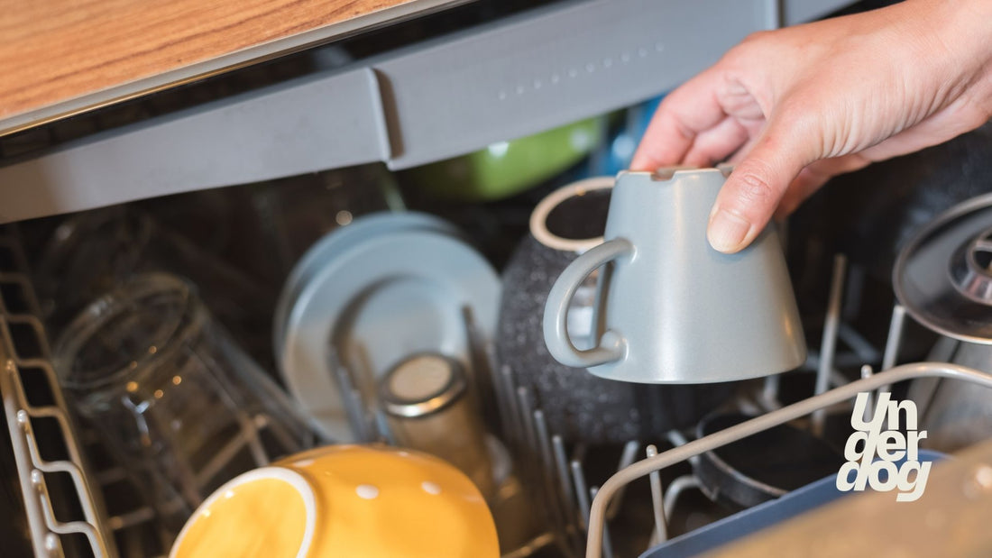 Une personne dépose une tasse dans un lave-vaisselle.