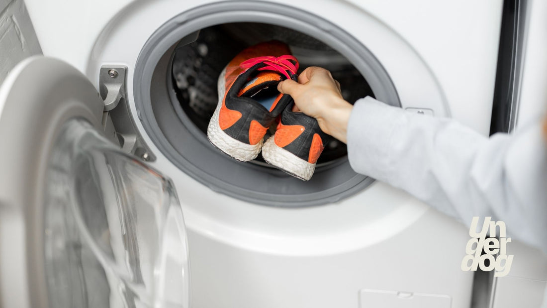 Une personne dépose des chaussures de sport dans un lave-linge.