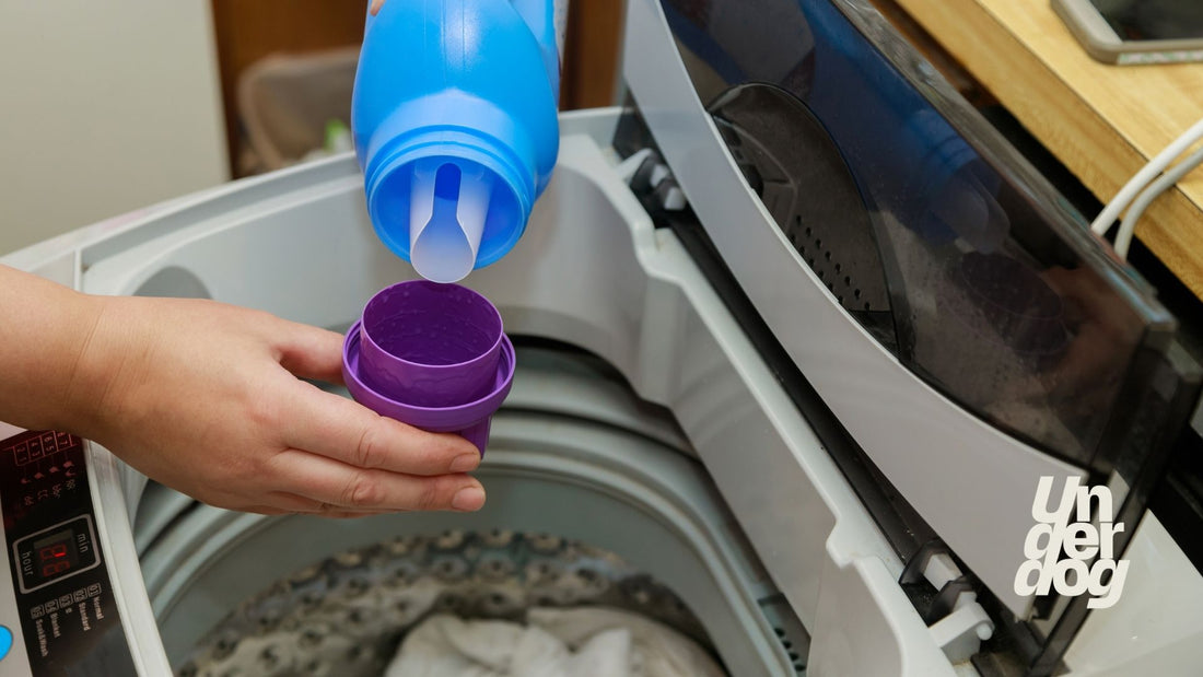 Une personne verse de la lessive dans un bouchon doseur au-dessus d'un lave-linge.