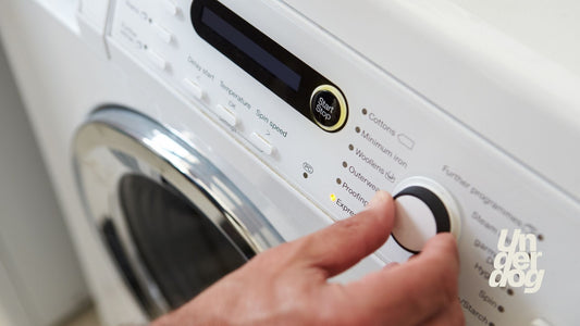 Une main ajuste le programme d'un sèche-linge.