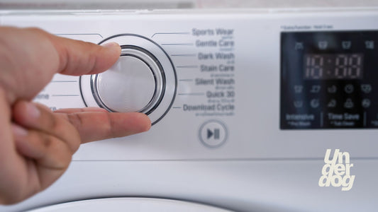 Une personne ajuste le programme d'un lave-linge.