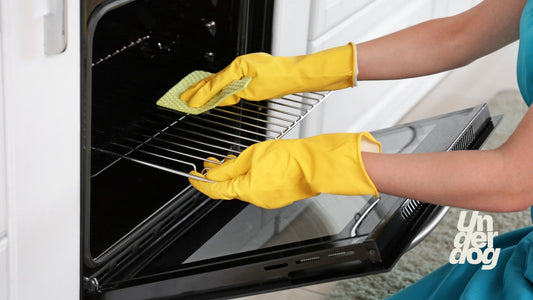 Une femme nettoie la grille d'un four.