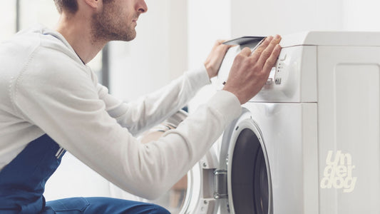 Un technicien répare un lave-linge.
