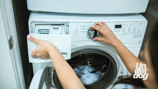 Une femme ouvre le bac à lessive d'un lave-linge.