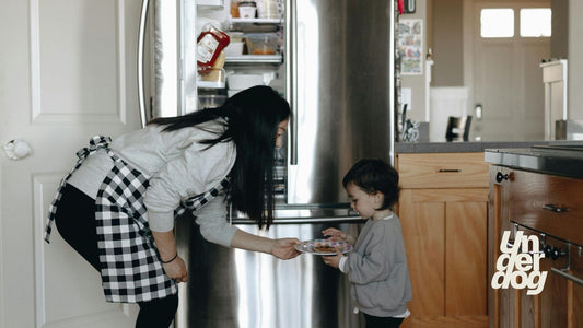 Une mère tend une assiette à son enfant dans la cuisine.