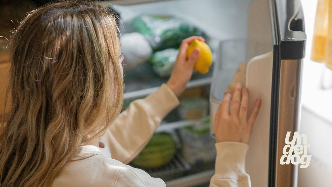 Une femme dépose un citron dans son réfrigérateur.