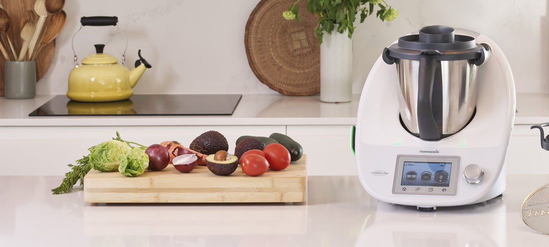 Un thermomix TM5 posé dans une cuisine avec des fruits et légumes à cotés
