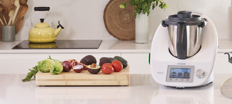 Un thermomix TM5 posé dans une cuisine avec des fruits et légumes à cotés