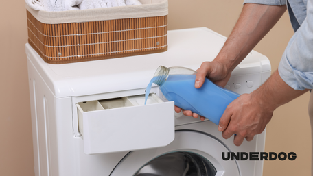 Une personne verse de la lessive dans le bac à lessive d'un lave-linge