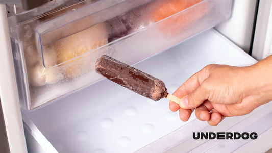 Un personne avec une glace à la main devant un congélateur