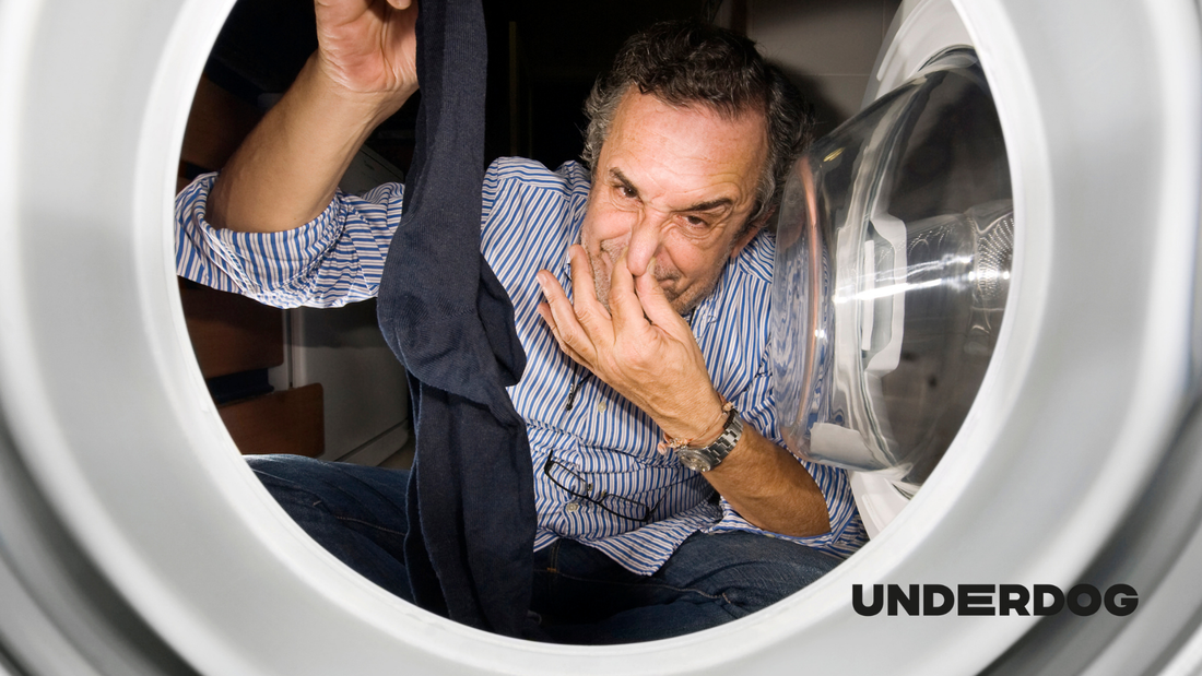 Un homme tient une chaussette dégageant une odeur désagréable