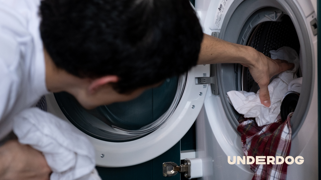 Une personne dépose du linge dans un lave-linge.