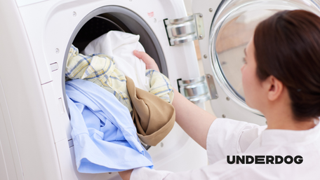 Une personne dépose du linge dans un lave-linge séchant