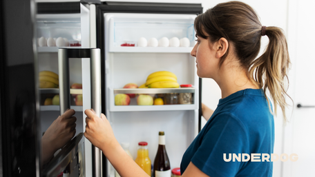 Une femme place un aliment dans son réfrigérateur