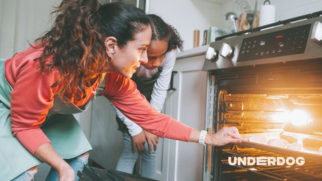 Une mère et sa fille enfournent un plat dans un four