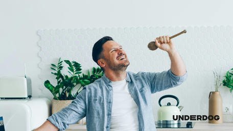 Un homme chante avec une cuillère en bois dans sa cuisine