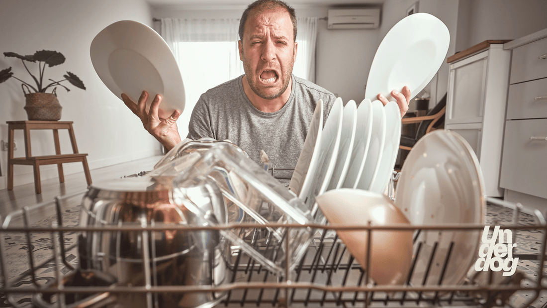 Un homme avec des assiettes dans les mains fait une grimace.