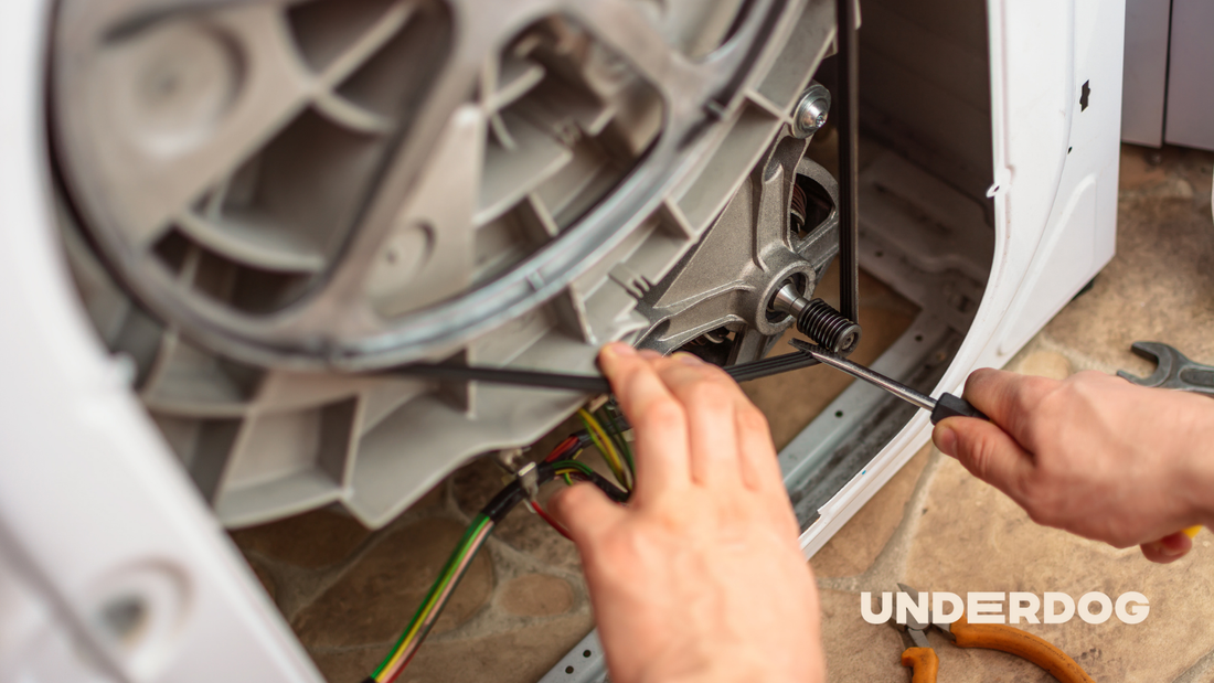 Un technicien répare la poulie d'un lave-linge.