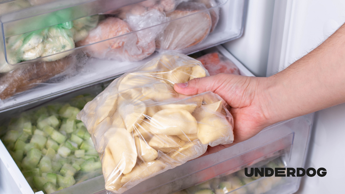 Une main saisit des pâtes congelées dans un congélateur