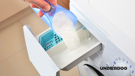 Une personne ajoute de la lessive dans le compartiment de son lave-linge