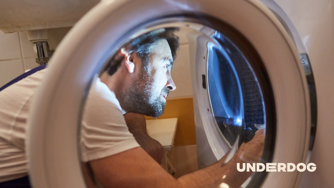 Un homme répare son lave-linge.