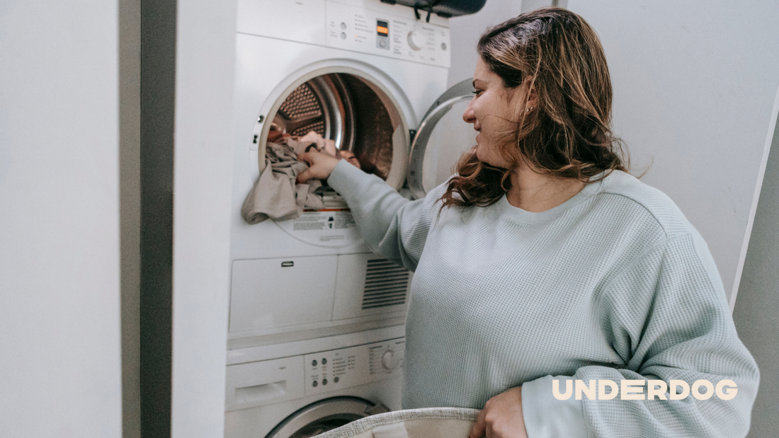 Un femme met du linge dans son sèche-linge