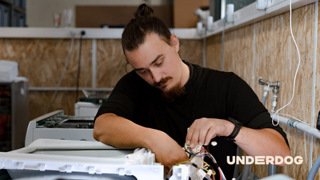 Un technicien répare un lave-vaisselle dans un entrepôt