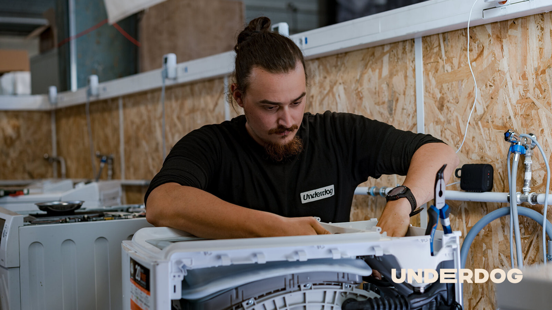Un technicien répare un lave-linge