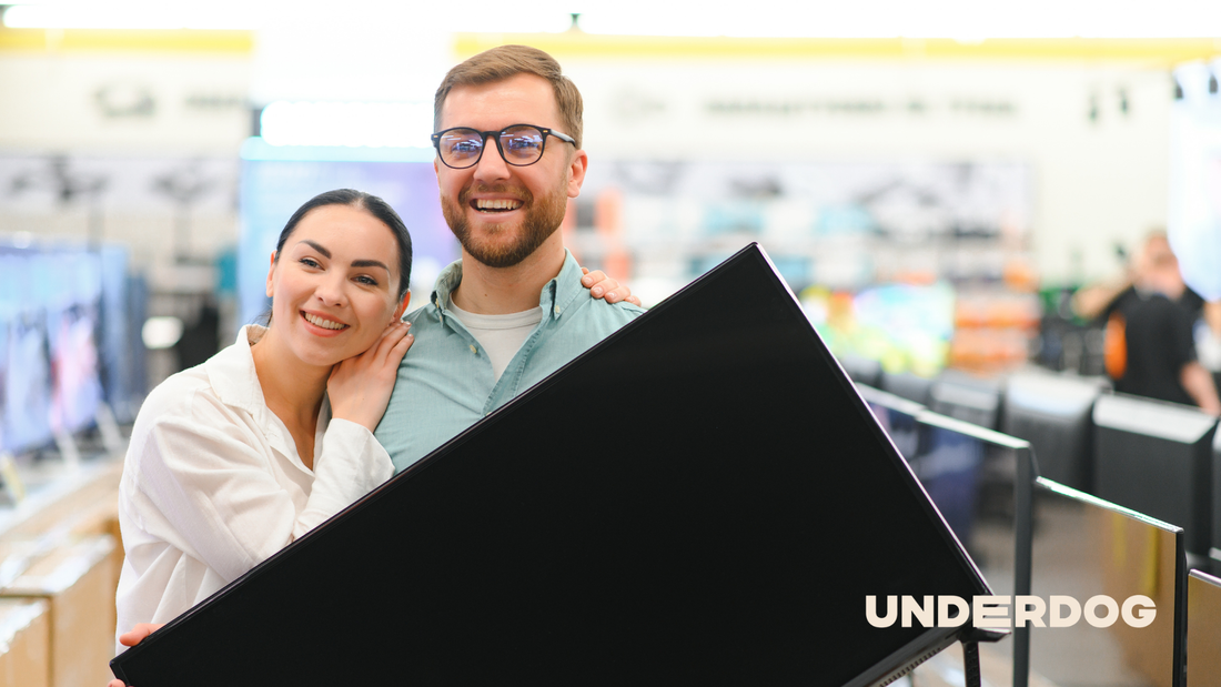Un couple avec une télévision 140 cm dans les mains après avoir acheté une télévision dans un magasin d’électroménager