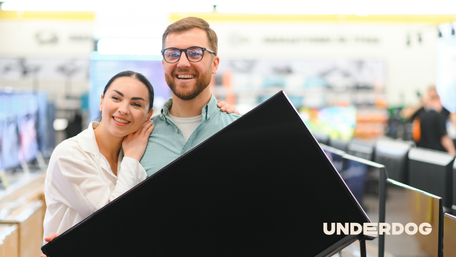 Un couple avec une télévision 140 cm dans les mains après avoir acheté une télévision dans un magasin d’électroménager