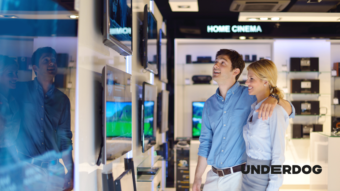 Un couple est en train de choisir une technologie de télévision adaptée à leurs besoins dans un magasin d’électroménager
