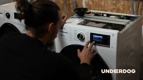 Un technicien répare un lave-linge dans un atelier