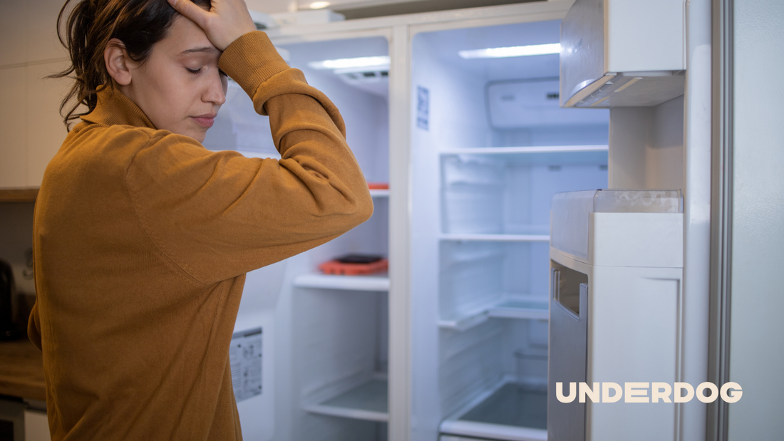Une personne se tient la tête devant son réfrigérateur