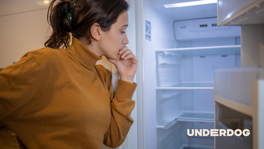 Un femme réfléchi devant son réfrigérateur