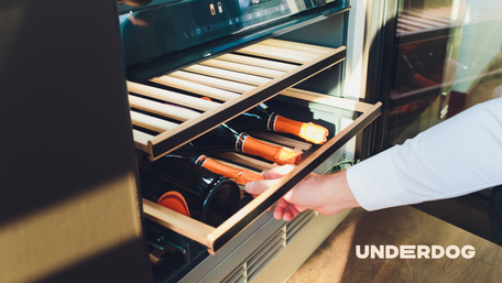 Un homme saisit une bouteille dans une cave à vin