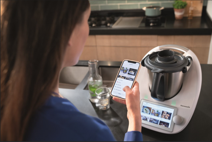 femme de dos devant son robot de cuisine Thermomix