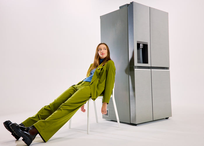 femme en vetement vert assise sur une chaise devant un frigo américain